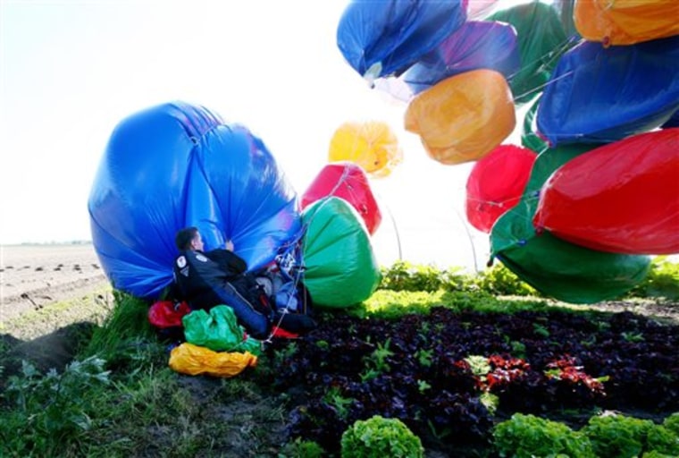 American cluster balloonist Jonathan Trappe holds onto his balloons after landing on farmland in Moeres, France, Friday May 28, 2010. Trappe took off from Challock, England, to become the first person to cross the English Channel in a chair attached to helium balloon. Trappe had been planning the flight for several months, after setting a world record for the longest free-floating balloon flight of 14 hours in the skies above North Carolina.(AP Photo/Gareth Fuller-pa)  **UNITED KINGDOM OUT: NO SALES: NO ARCHIVE:**